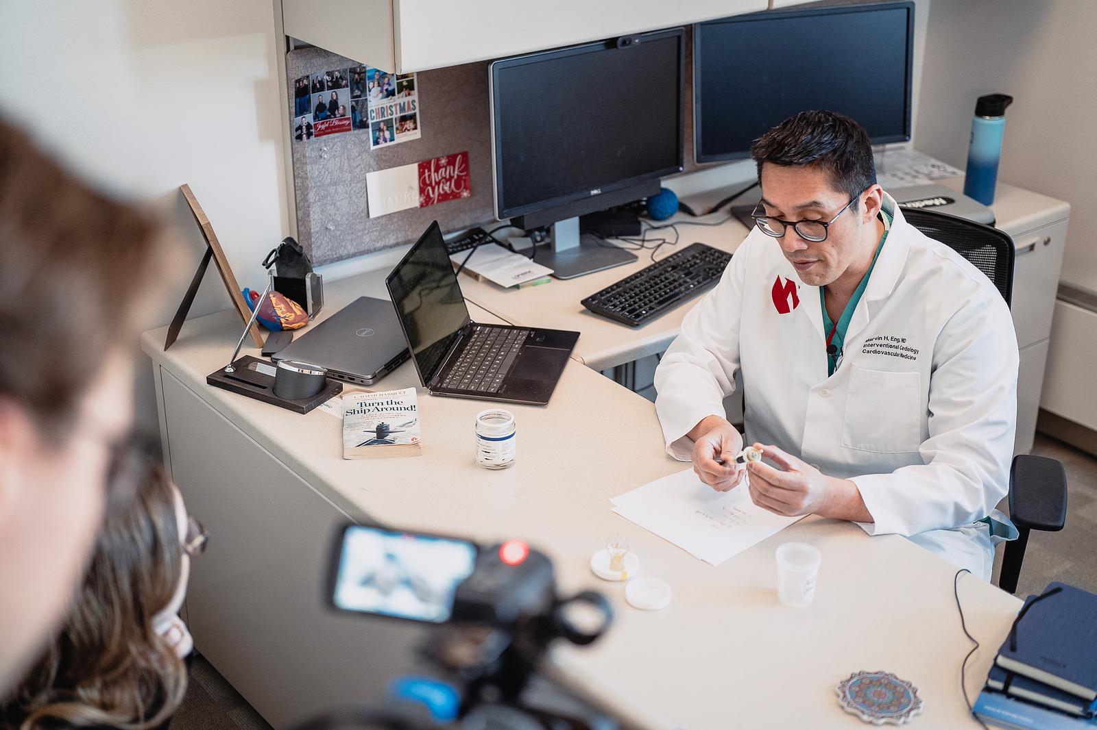 Marvin Eng, MD, shows 10/11 News anchor Madison Pitsch how various heart devices work.